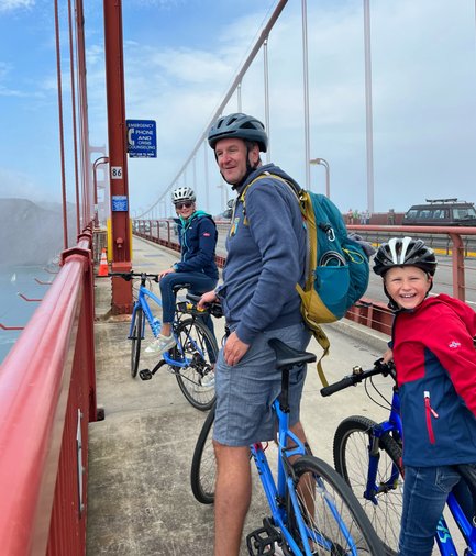 Eine Familie mit Fahrrädern genießt den Blick auf die Golden Gate Bridge, während sie auf der Brücke posiert.