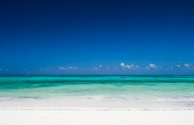Ein atemberaubender Blick auf den klaren, türkisfarbenen Ozean, der sanft an den weißen Sandstrand plätschert.