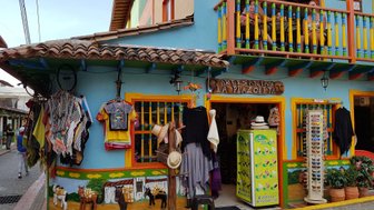Bunte Fassade eines Geschäfts in Guatapé, mit handgefertigten Kleidungsstücken und einem lebhaften Balkon im Obergeschoss.