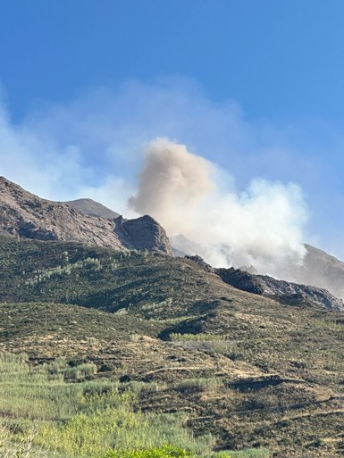 Der Stromboli Vulkan spuckt Rauch und Asche in den klaren blauen Himmel über der zerklüfteten Landschaft.