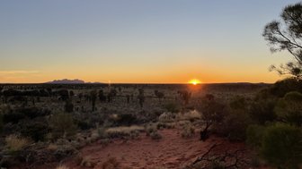 Die untergehende Sonne taucht die endlose Wüstenlandschaft in lebendige orangefarbene und goldene Töne.