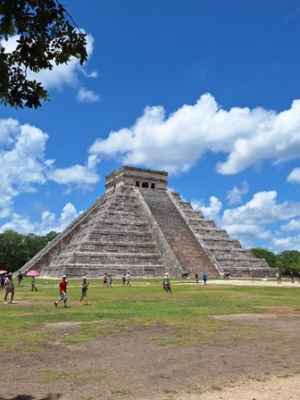 Die beeindruckende Pyramide von Chichén Itzá erhebt sich majestätisch unter einem strahlend blauen Himmel mit weißen Wolken.