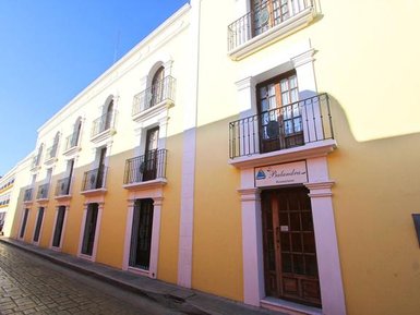 Eine gelbe Gebäudeansicht mit mehreren Fenstern und Balkonen, die eine einladende Atmosphäre ausstrahlt.