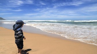 Kind steht an der Küste und blickt aufs Meer – Garden Route mit Kindern