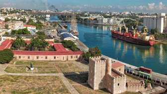 Ein Blick auf die Festung Ozama in Santo Domingo, umgeben von grünen Bäumen und dem glitzernden Wasser des Flusses.