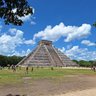 Die beeindruckende Pyramide von Chichén Itzá erhebt sich majestätisch unter einem strahlend blauen Himmel mit weißen Wolken.