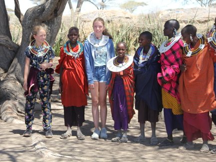 Kinder aus Reisegruppe posieren gemeinsam mit einer Massai-Familie – Tansania Familienreise