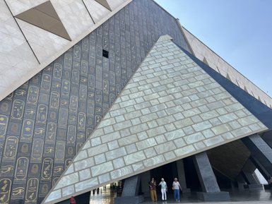 Moderne Architektur des Neuen Ägyptischen Museums mit einer markanten Pyramidenform und Hieroglyphen an der Wand.