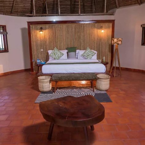 Ein stilvolles Schlafzimmer mit einem großen Bett, umgeben von warmem Licht und natürlichen Materialien, strahlt Gemütlichkeit aus.