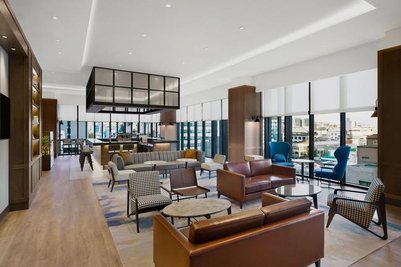 Ein eleganter Loungebereich mit modernen Möbeln und großen Fenstern, die einen Blick auf die Stadt bieten.