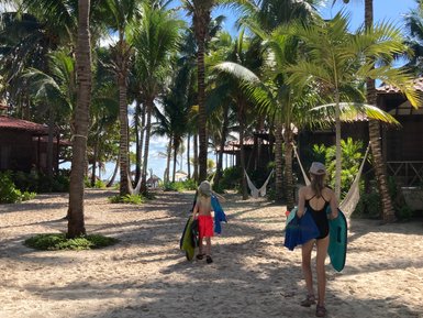 Zwei Kinder laufen barfuß über den Sand in Richtung Strand von Playa del Carmen – Mexiko Familienreise