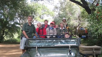 Eine Familie sitzt im offenen Safari-Jeep in Makutsi – Südafrika mit Kindern