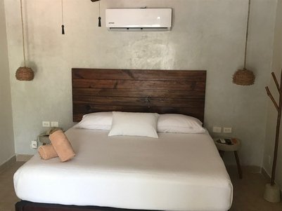 Ein gemütliches Schlafzimmer mit einem großen Bett, Holzdetails und einer Klimaanlage an der Wand.