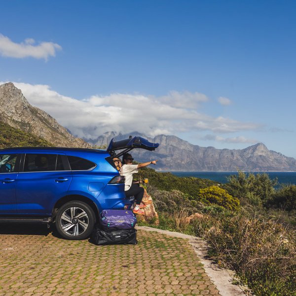 Mutter sitzt im Kofferraum vom Auto und genießt Ausblick – Südafrika Reise mit Kindern