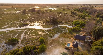 Eine weitläufige Landschaft im Okavango mit üppigem Grün und Wasserläufen, die durch das Gelände fließen.