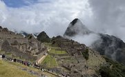 Die beeindruckenden Ruinen von Machu Picchu liegen majestätisch zwischen den Wolken und den grünen Bergen Perus.