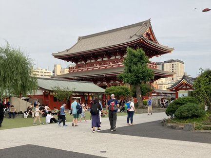 Besucher schlendern durch den weitläufigen Tempelbereich, umgeben von traditioneller Architektur und grünen Pflanzen.