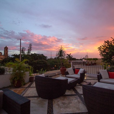 Eine gemütliche Terrasse mit modernen Möbeln bietet einen atemberaubenden Blick auf die bunten Wolken des Sonnenuntergangs.