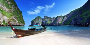 Küstenabschnitt mit Felsformationen und traditionellem Boot – Thailand Reise mit Kindern