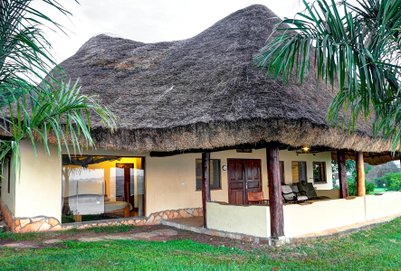 Ein gemütliches, strohgedecktes Haus mit einer Veranda, umgeben von üppigem Grün und Palmen, ideal für Entspannung.