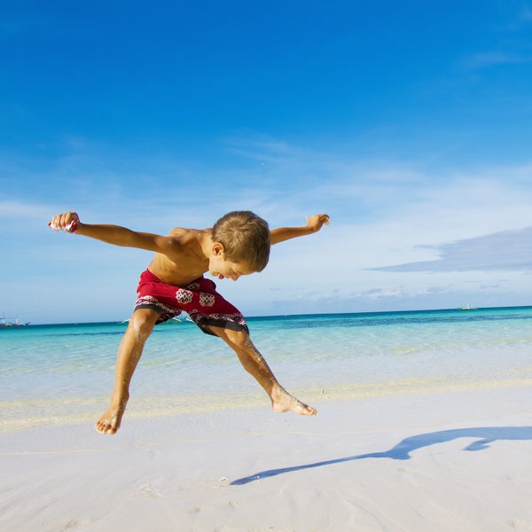 Junge springt am Sandstrand von Mexiko – Mexiko Familienreise