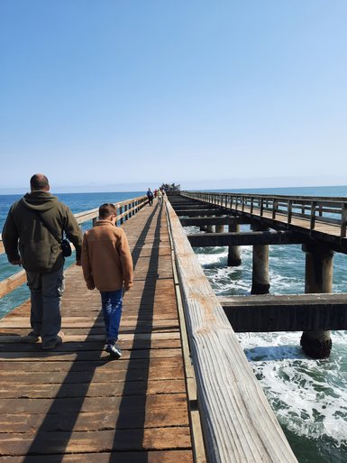 Zwei Menschen laufen einen langen Bootssteg entlang - Namibia mit Jugendlichen