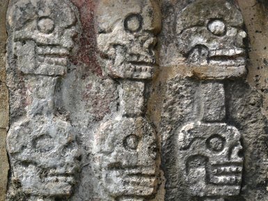 Detail einer antiken Steingravur mit Totenkopfmotiven am Tempel von Kukulcán – Mexiko Reise mit Kindern