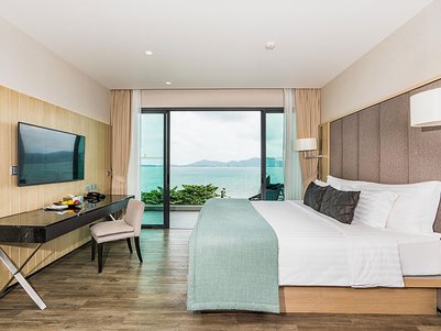 Ein modernes Hotelzimmer mit einem großen Fenster, das einen Blick auf das Meer und die Berge bietet.