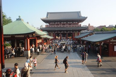 Eine belebte Szene vor dem Senso-ji Tempel in Asakusa, Tokio, mit vielen Besuchern und traditioneller Architektur.