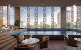 Ein eleganter Innenpool mit blauen Fliesen, umgeben von großen Fenstern und modernen Liegen, die zum Entspannen einladen.