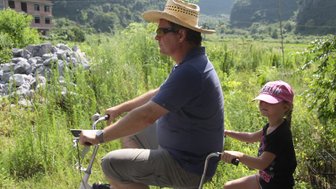 Vater und Kind entdecken gemeinsam die Landschaft von Yangshuo auf einer Fahrradtour – China Familienreise