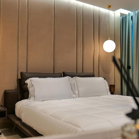 Ein modernes Hotelzimmer mit einem großen Bett, sanften Farben und stilvollen Lampen, die eine gemütliche Atmosphäre schaffen.