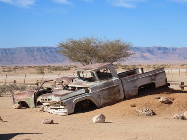 Ein rostiges Auto steht verlassen in der Wüste - Namibia mit Kindern