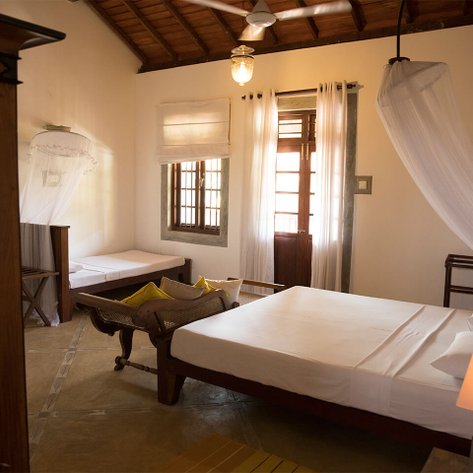 Ein helles Zimmer mit einem großen Bett, einem Holzstuhl und einem Fenster, das Tageslicht hereinlässt.