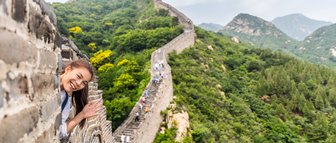 Teenager grüßt von der Großen Mauer mit weitem Blick auf die Landschaft Chinas – China Reise mit Kindern