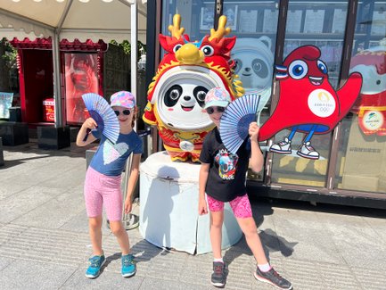 Kinder posieren mit traditionellen Fächern vor einer Pandafigur – China mit Kindern