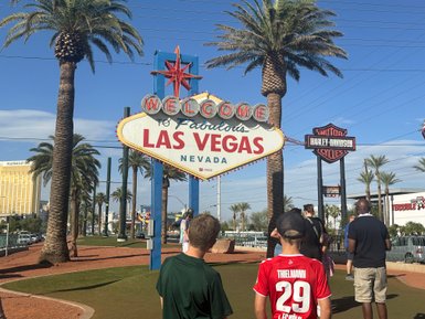 Der berühmte Las Vegas-Schild begrüßt Besucher mit Palmen und strahlend blauem Himmel im Hintergrund.