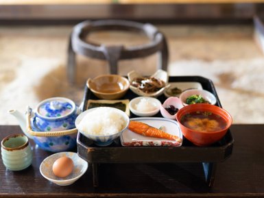 Ein traditionelles japanisches Frühstück auf einem Tisch, bestehend aus Reis, Fisch, Miso-Suppe und verschiedenen Beilagen.