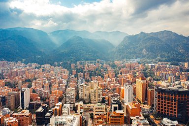 Eine weite Aussicht auf Bogotá, umgeben von majestätischen Bergen, mit einer Vielzahl von orangefarbenen Gebäuden im Vordergrund.