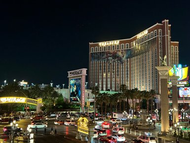 Die belebte Las Vegas Boulevard bei Nacht, mit hellen Lichtern und dem Treasure Island Hotel im Hintergrund.