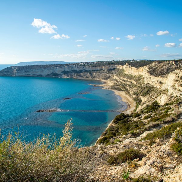 Eine atemberaubende Küstenlandschaft mit klarem, blauem Wasser und sanften Hügeln, die sich entlang der Küste erstrecken.