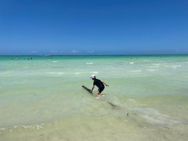Junge spielt im klaren Wasser vor der Küste von Holbox – Mexiko mit Kindern