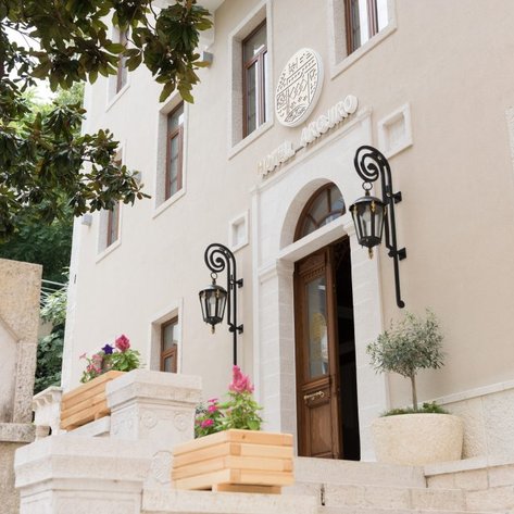 Der Eingangsbereich des Hotel Argjiro zeigt eine elegante Fassade mit großen Fenstern und stilvollen Laternen.