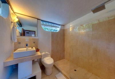 Ein modernes Badezimmer mit einer großen Dusche, einem Waschbecken und einem WC, alles in warmen Erdtönen gestaltet.
