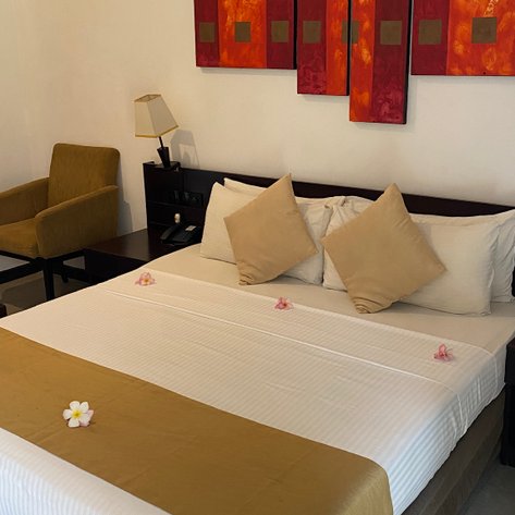 Ein stilvolles Hotelzimmer mit einem großen Bett, dekoriert mit Kissen und Blumen, strahlt Ruhe und Eleganz aus.