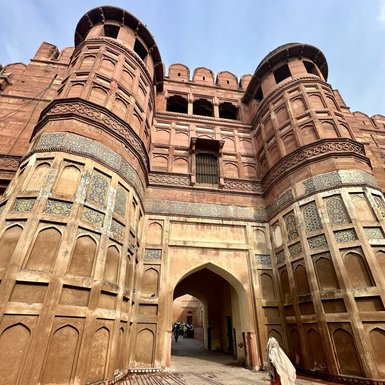 Die beeindruckende Fassade des Agra Forts zeigt kunstvolle Verzierungen und massive Türme unter einem klaren Himmel.