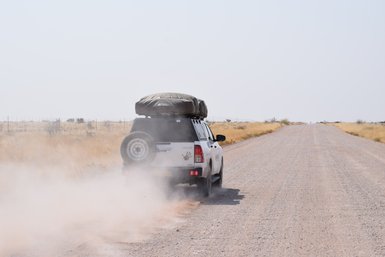 Ein Jeep mit Dachzelt fährt über eine unbefestigte Straße - Namibia mit Kindern