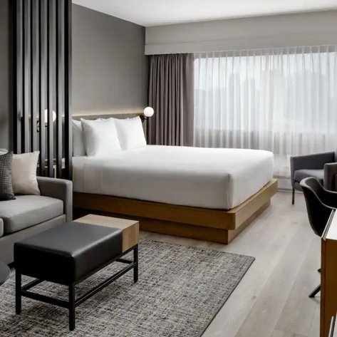 Ein modernes Hotelzimmer mit einem großen Bett, einem gemütlichen Sofa und einem eleganten Schreibtisch, das einladend wirkt.