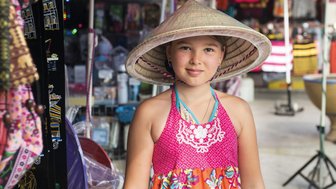 Mädchen trägt traditionellen Strohhut in Vietnam – Vietnam mit Kindern