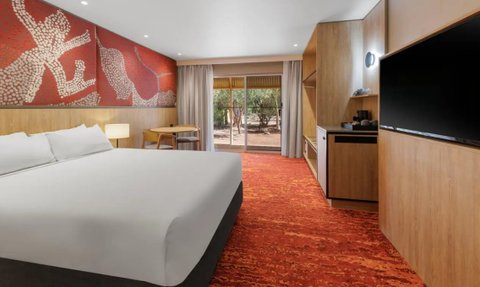 Der Raum zeigt ein modernes Hotelzimmer mit einem großen Bett und einem einzigartigen roten Kunstwerk an der Wand.